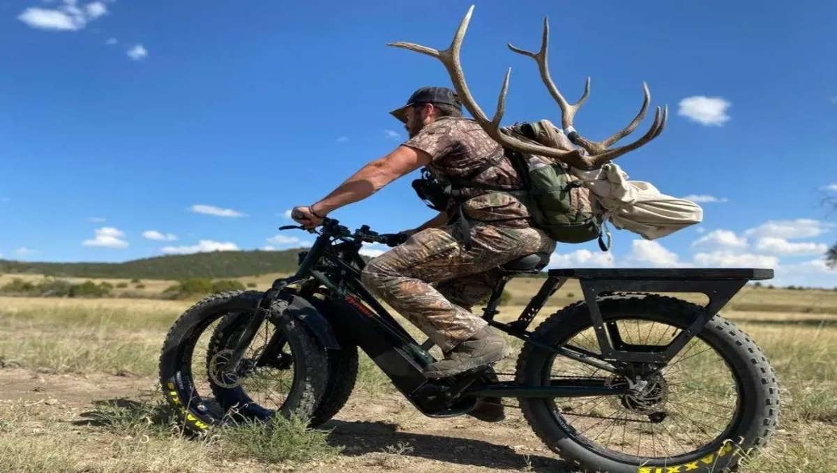 Man riding ebike with hunting accessories