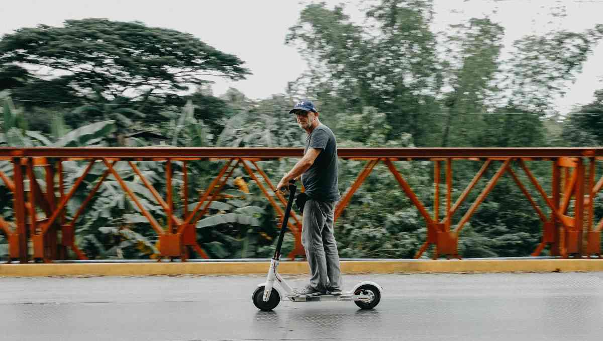 ebike vs scooter - man riding scooter on the bridge