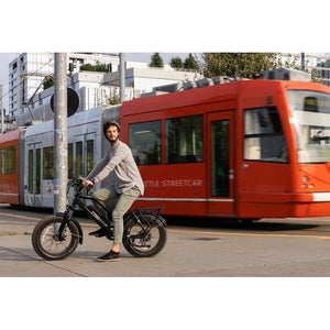 Troxus-Skyhopper-750W-Step-Thru-Fat-Tire-Electric-Bike-Step-Through-Troxus-Mobility - Man riding an ebike with red train background 